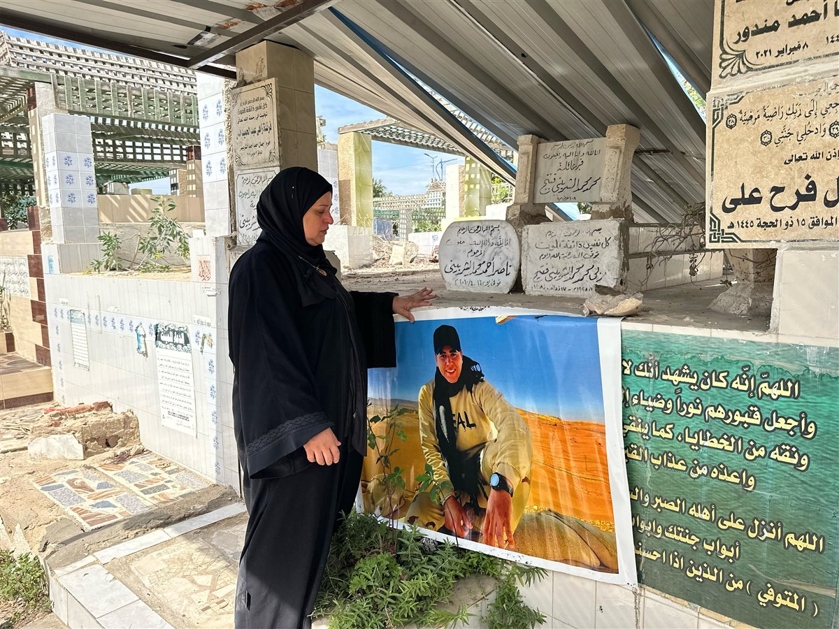 الأم المكلومة تقف على قبر الشهيد