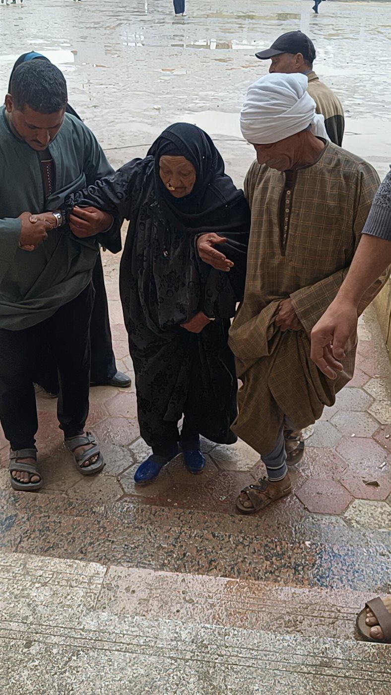 مسنة عمرها 85 عامًا على كرسي متحرك تتحدى المطر للإدلاء بصوتها في لجنة مدرسة اللواء أحمد عبد التواب بطامية