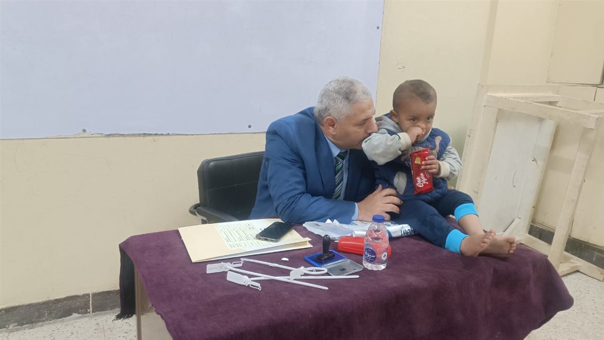 في موقف انساني.. رئيس لجنة في الفيوم يحمل طفل ناخب ليمكن والده من الانتخاب