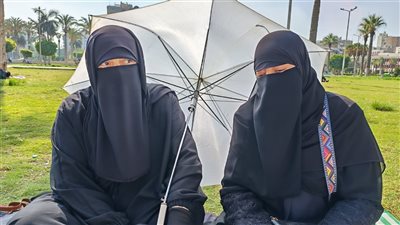 بالمظلة.. شقيقتان تنتظران نجليهما أمام لجنة امتحان الثانوية العامة ببورسعيد