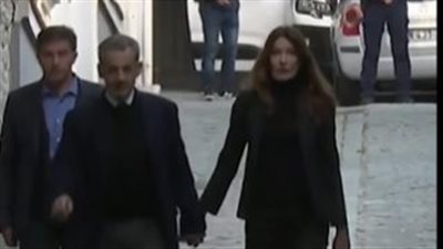 بيد في يد.. زوجة رئيس فرنسا الأسبق ترافقه إلى السجن وسط حشد داعميه